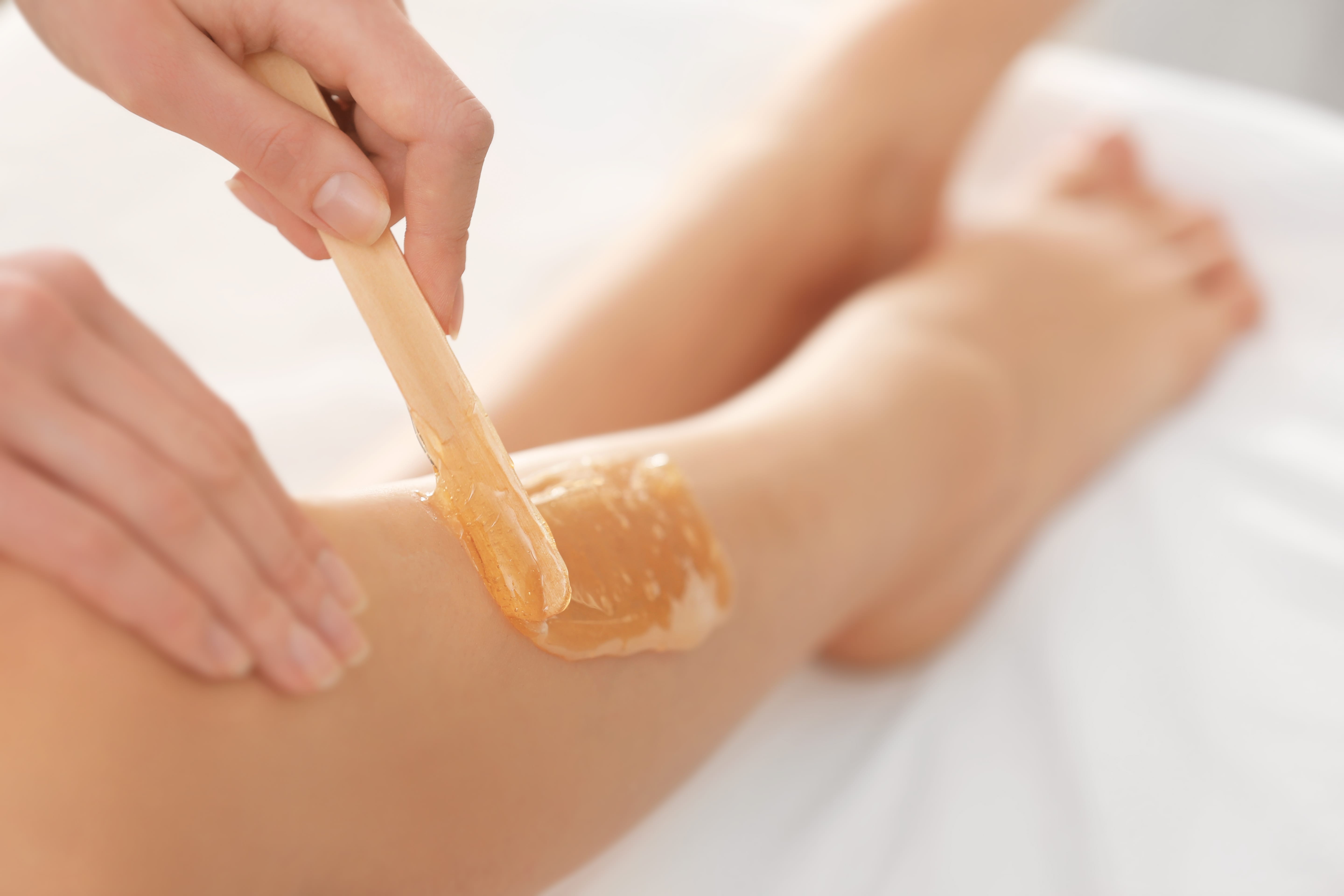 Beautician waxing female legs in spa center | Ella Esthetics in Alexandria, VA