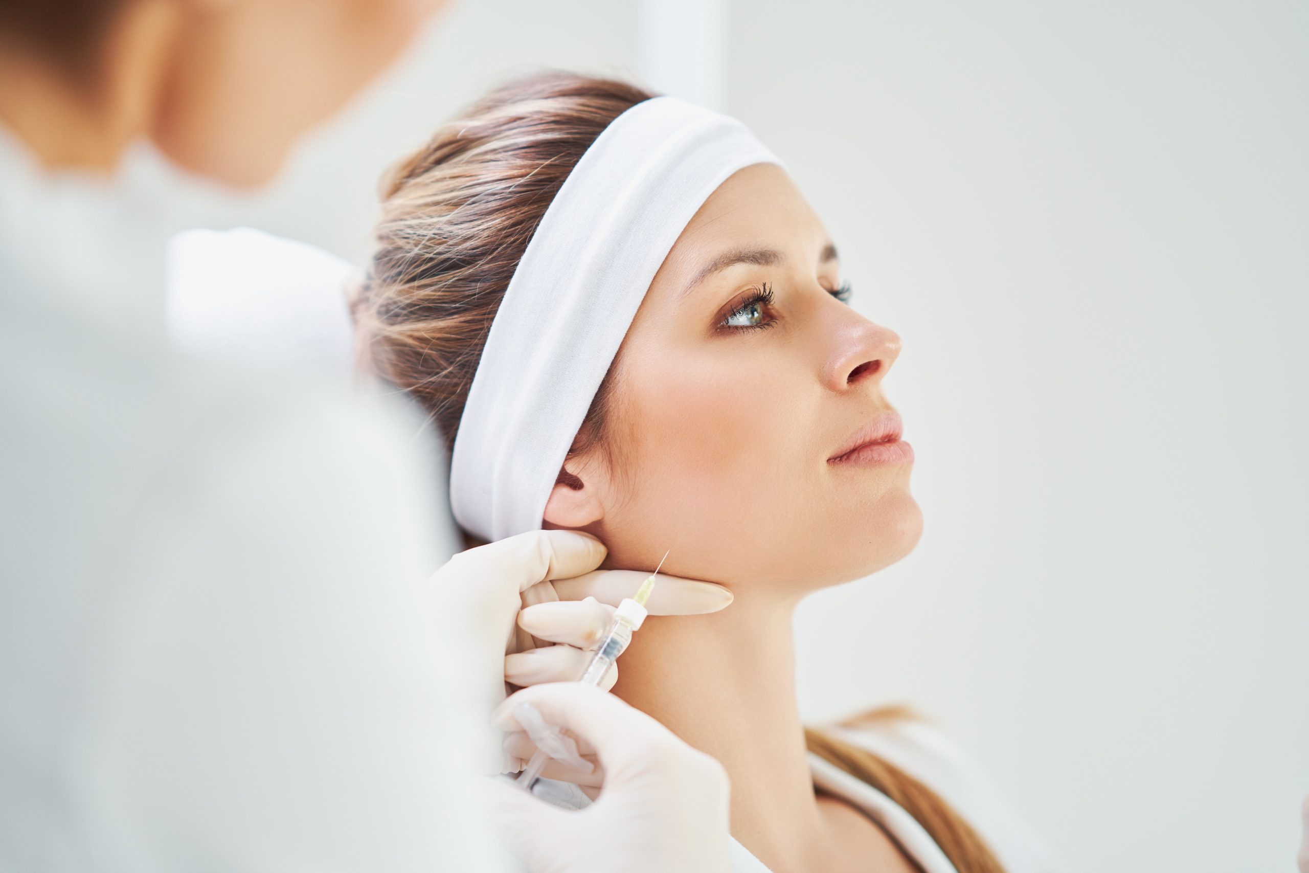 Close up portrait of blonde woman with cosmetologist hands giving botox injection | Ella Esthetics in Alexandria, VA