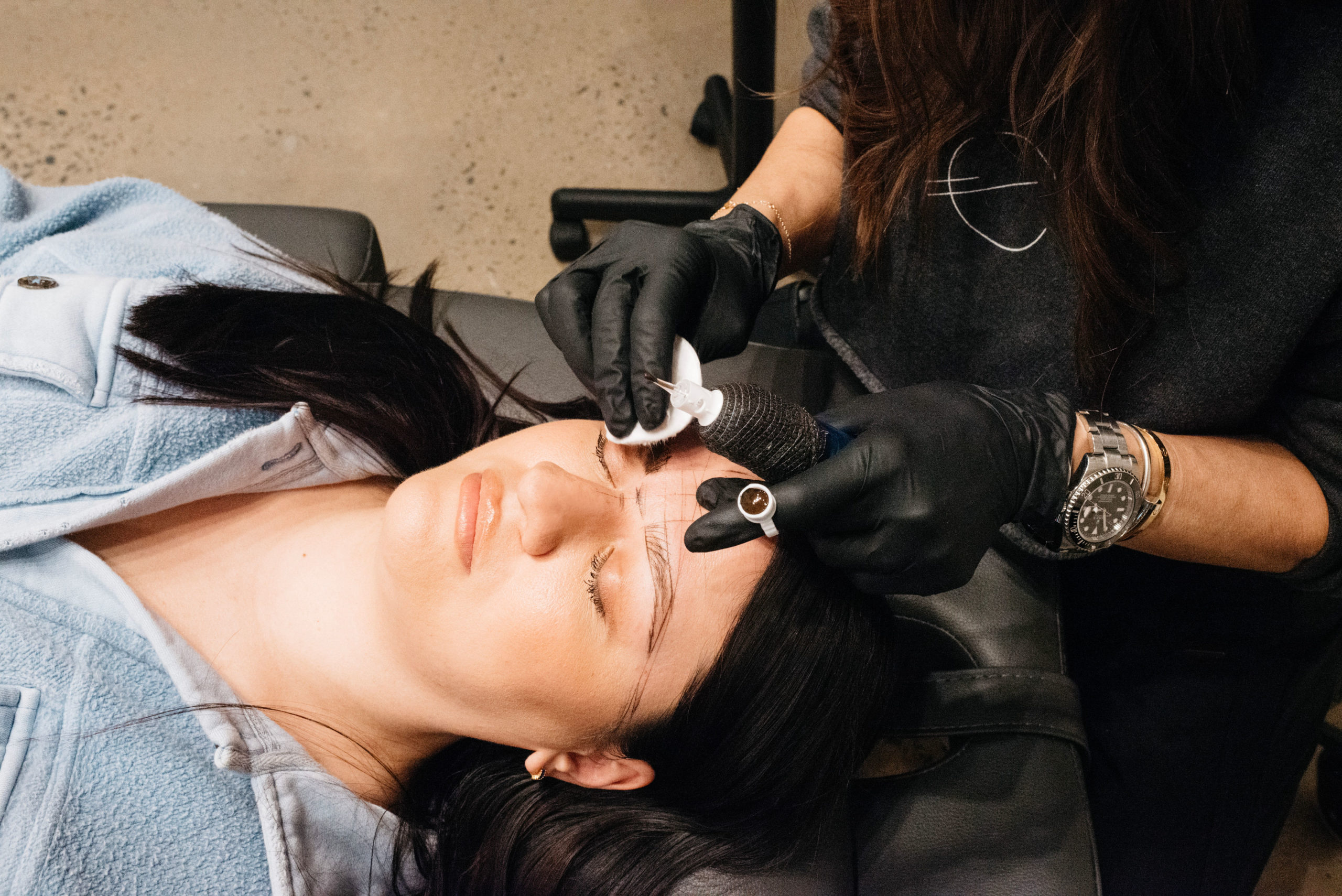 Eyebrows microblading concept. Cosmetologist preparing young woman for eyebrow permanent makeup procedure and Clinic with beauty products in a Spa | Ella Esthetics in Alexandria, VA