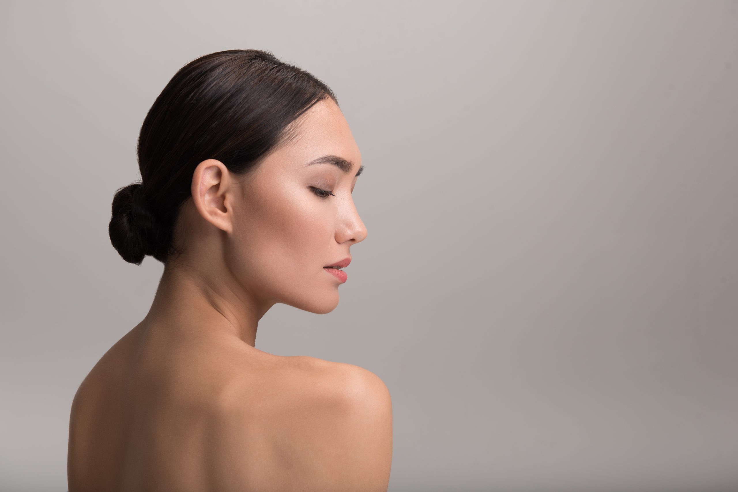 Skincare and beauty concept. Profile of charming serious young asian girl is looking down thoughtfully while demonstrating her perfect and fresh skin. Isolated background with copy space in right side | Ella Esthetics in Alexandria, VA